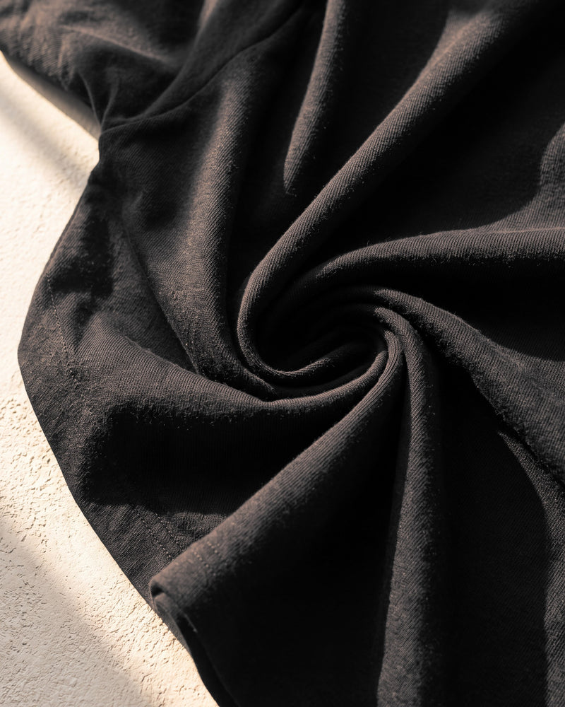 Combed cotton single jersey on a black 240 gsm The Word tee in warm sunlight