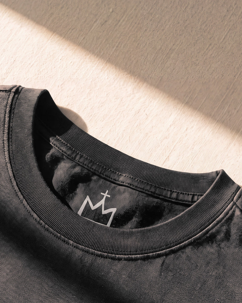 Double-stitched ribbed collar with the crown neck logo behind it on a black 240 gsm The Word tee