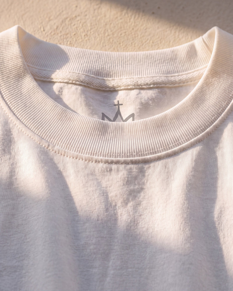 Double-stitched ribbed collar with the crown neck logo behind it on a white 240 gsm The Word tee