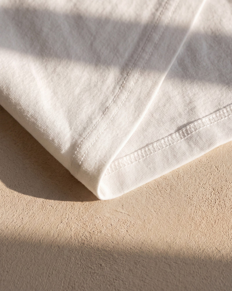 Coverstitch hem on a white 240 gsm The Word tee in warm sunlight