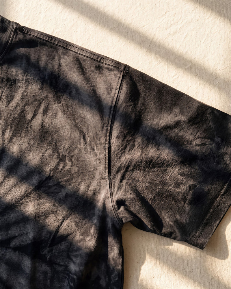 Crinkle tie-dye and washed effect on the shoulder of a faded black The Word tee