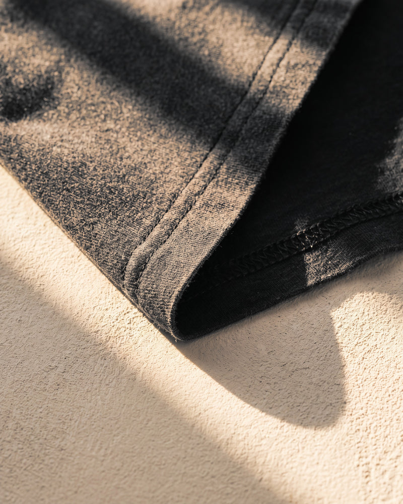 Coverstitch hem on a faded black 260 gsm The Word tee in warm sunlight