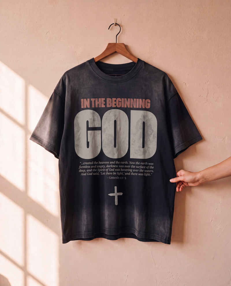 In the Beginning God faded black tee on a hanger, front print