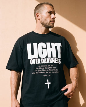 Light Over Darkness tee, black, front print, man, hand on hem thigh up