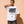 Light Over Darkness tee, white, front print, woman, hand on neck thigh up