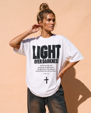 Light Over Darkness tee, white, front print, woman, hand on hip thigh up